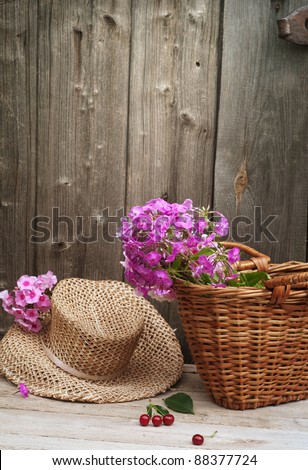 basket of flowers and a straw hat against the background of the old wooden walls