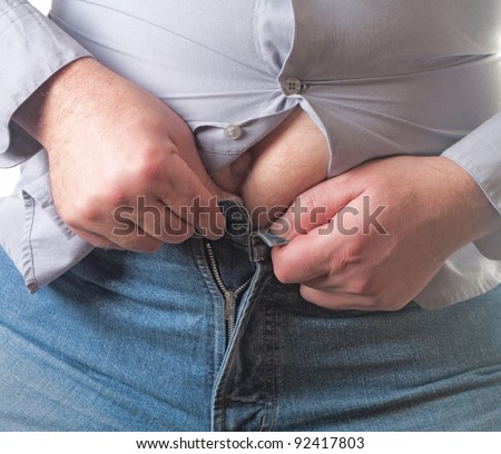 Overweight man trying to fasten too small clothes isolated on white background