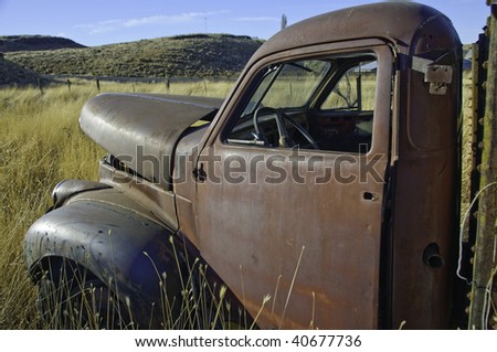 Old studebaker truck rusting in the farm field.It has the morning sun on it.
