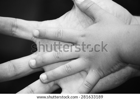 Put your tiny hand in mine.  This is a black & white photograph of a child\'s hand on an adult\'s hand.  It is a close up and it is gender neutral.