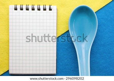 Menu background. Cook book. Recipe notebook on a blue and yellow background. Clay spoon and Notepad.