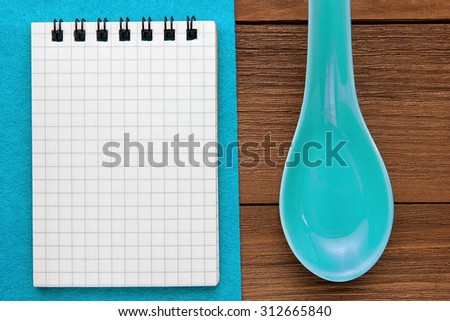 Menu background. Cook book. Recipe note book on a blue background and a wooden texture. Clay spoons and a Notepad.