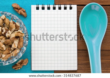 Menu background. Cook book. Recipe notebook with walnuts on a blue background and a wooden board.