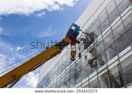 Mobile crane basket with the man working on the high building to clean the glasses