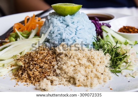 Rice mix salad , Thai cuisine , Thai Southern food, Spicy blue rice salad with mix vegetable on white plate ready to serve.