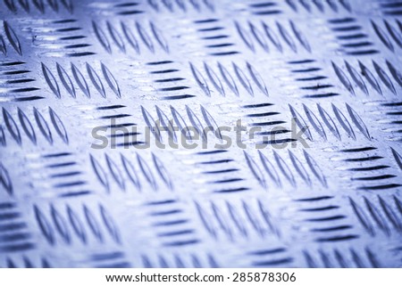 Blue colored Diamond plate also known as checker plate, tread plate, cross hatch kick plate and Durbar floor plate, closeup with shallow depth of focus in landscape orientation.