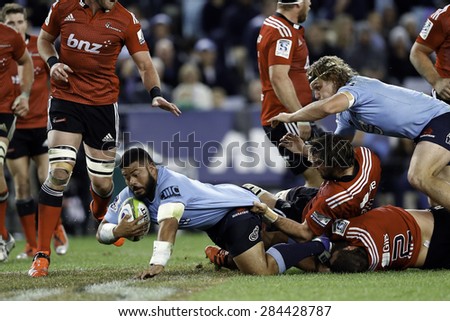 SYDNEY AUSTRALIA-MAY 2015, Tolu Latu (blue) of the NSW Waratahs breaking through the Crusaders players during the Super Rugby match at the ANZ Stadium, Sydney on 23 May, 2015, in Australia