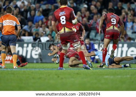 SYDNEY AUSTRALIA-June 2015, Karmichael Hunt (red) is tackled by a NSW Waratahs player during their Super Rugby clash at the Allianz Stadium, Sydney on 13 June 2015, in Australia