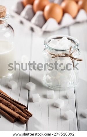 Eggs, milk, cinnamon, white sugar on wooden table