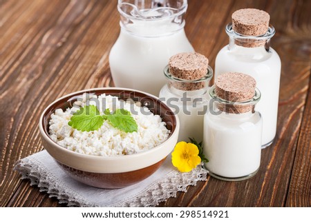 Bowl of cottage cheese and milk in glass container on wooden table