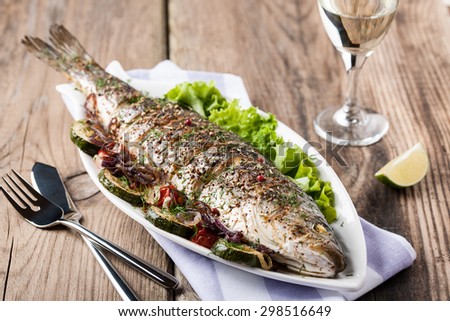 Baked fish with vegetables and a glass of white wine