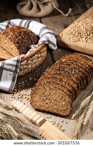 Loaves of rye bread, rye ears, barley grain and bread knife on the  wooden table