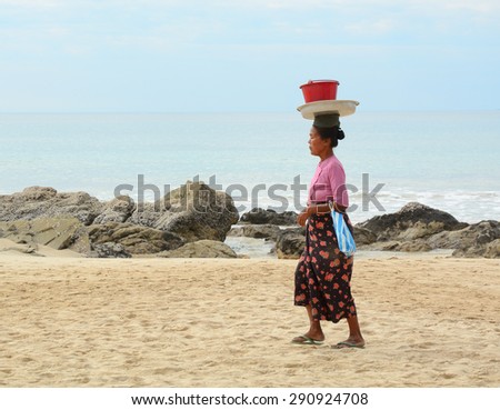 NGAPALI, MYANMAR - JAN 16, 2015. Unidentified woman selling fresh fruits at the shoreline to tourists in Ngapali beach. Selling products to the tourists is the main income for people in Ngapali.