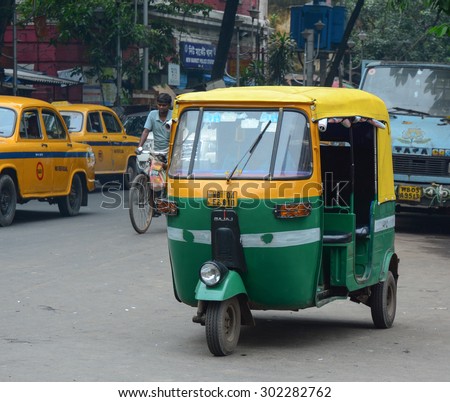 KOLKATA, INDIA - JUL 8, 2015. Private auto rickshaw three-weeler tuk-tuk taxi drives down the street in Kolkata. Indian three-wheelers have the design of the Piaggio Ape C, from 1948.