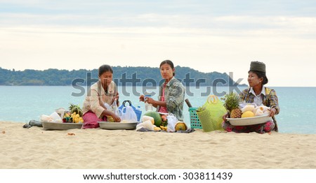 NGAPALI, MYANMAR - JAN 16, 2015. Unidentified women selling fresh fruits at the shoreline to tourists in Ngapali beach. Selling products to the tourists is the main income for people in Ngapali.