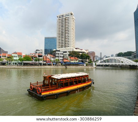 Singapore - June 1, 2015. View of tourist boat floating on Singapore river with downtown buildings in the background.