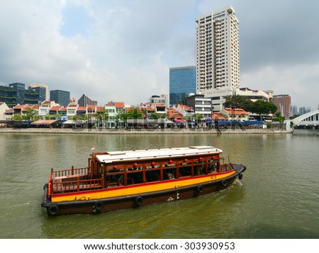 Singapore - June 1, 2015. A tourist boat floating on Singapore river with downtown buildings in the background.