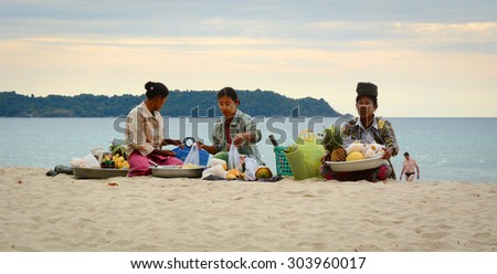 NGAPALI, MYANMAR - JAN 16, 2015. Unidentified women selling fresh fruits at the shoreline to tourists in Ngapali beach. Selling products to the tourists is the main income for people in Ngapali.