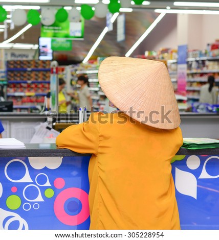 Saigon, Vietnam - Aug 1, 2015. An unidentified old woman with conical hat at Coopmart supermarket in Saigon, Vietnam.