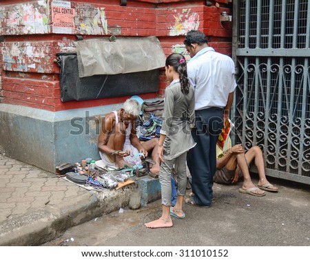 KOLKATA, INDIA - JUL 8, 2015. Unidentified shoe shiner does his job at street of Kolkata. Lots of people make their living by doing this job in India.