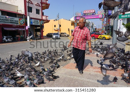 MALACCA, MALAYSIA - AUG 19, 2015. Pigeons waiting for feed at Little India in Malacca. Malacca City was listed as a UNESCO World Heritage Site on 7 July 2008.