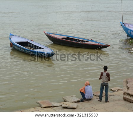 Varanasi, India - Jul 12, 2015. Indian men waiting for tourists taking the boat tour on the sacred Ganges river in Varanasi, Uttar Pradesh, India.