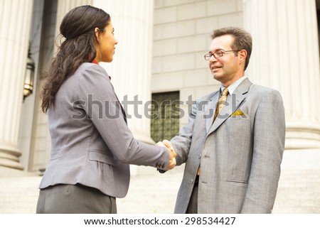 Business people or lawyers on outdoor steps shaking hands.