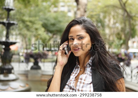 A woman with her cell phone looks at viewer.