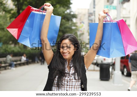 A woman holding shopping bags above her head.