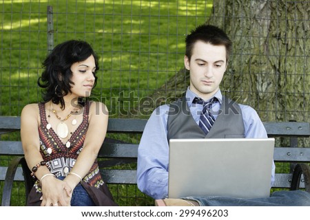 Man works on laptop as woman watches.