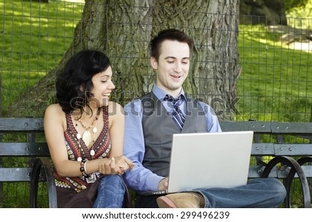 Man and woman look at laptop screen and laugh.