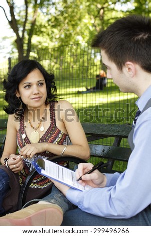 A man interviews a woman for a job or is taking a survey. Focus is on woman.