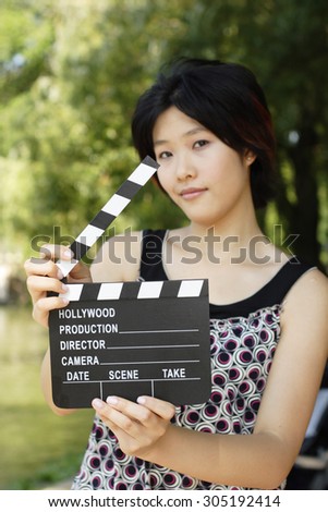 A beautiful woman holds an open film slate. Focus is on film slate.