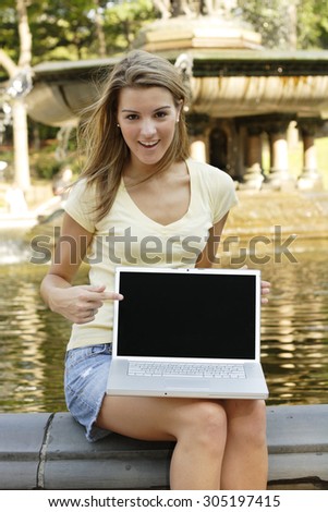 Young woman smiles and points to laptop screen.