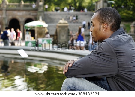 Man in profile sitting at fountain.