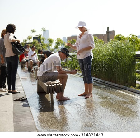 New York, New York, USA - May 12, 2011: People relaxing and cooling off in a water feature on The High Line.