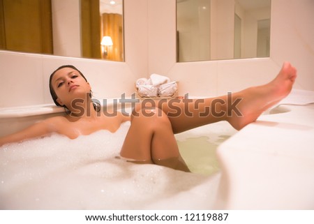 Young woman enjoys the bath-foam in the bathtub.