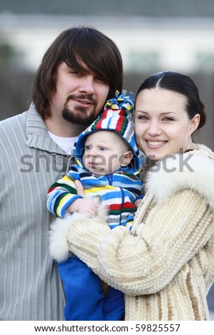 Portrait of a young and happy family outdoors. Young lovely couple outdoor holding new born baby and smiling in to the camera. blurry background.