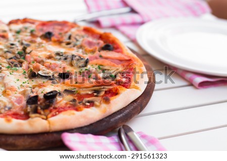 Delicious hot pizza with ham and mushrooms on wooden plate, on white table