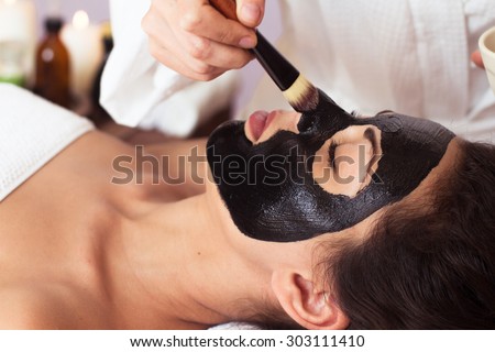Beautiful woman with facial mask at beauty salon. Spa treatment