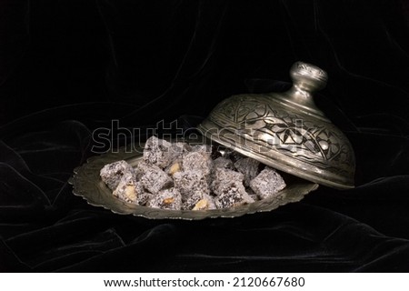 Turkish delight in hollowware on black velvet cover. Traditional Turkish sweet double roasted with pistachio nuts and coconut in a metal oriental bowl. Foto d'archivio © 