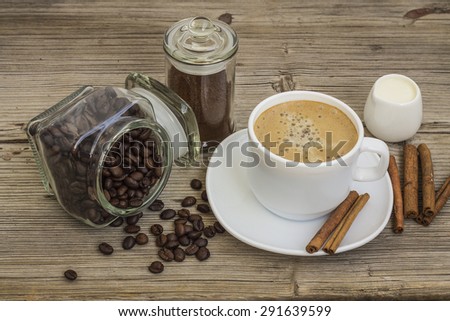 cup of coffee with milk and cinnamon and coffee beans