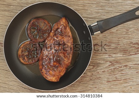 Protein. Meat fried in a frying pan with rosemary and lemon on the table of of wooden boards, knife, fork, rustic style. Top view. Free Zone for writing.