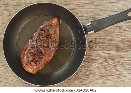 Protein. Meat fried in a frying pan with rosemary and lemon on the table of of wooden boards, knife, fork, rustic style. Top view. Free Zone for writing.