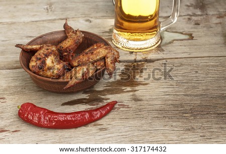Beer and chicken wings on a wooden table. Space for text