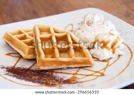 Butter waffles decorated on dish with whipping cream and caramel sauce