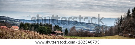 Panoramic view of cottage on mountain side along hiking trail up the Jura mountains in Pays-de-Gex, France, over-viewing the Mont-Blanc mountain range of the Alps. 2015.