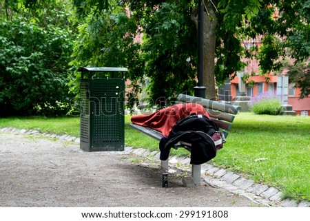 Homeless person sleeping in park, on bench. Stockholm, Sweden.