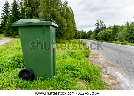 Trash bin by road in countryside.