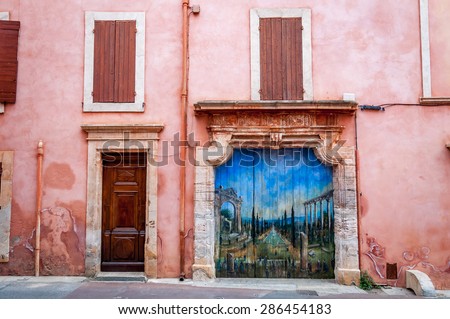 ROUSSILLON, FRANCE - APRIL 16, 2015: Painting of a French garden, including Roman ruins on a garage door. This is a famous landmark in a recently named \